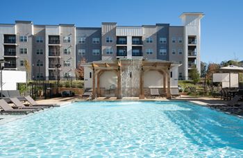 A large swimming pool in front of a multi-story apartment building.